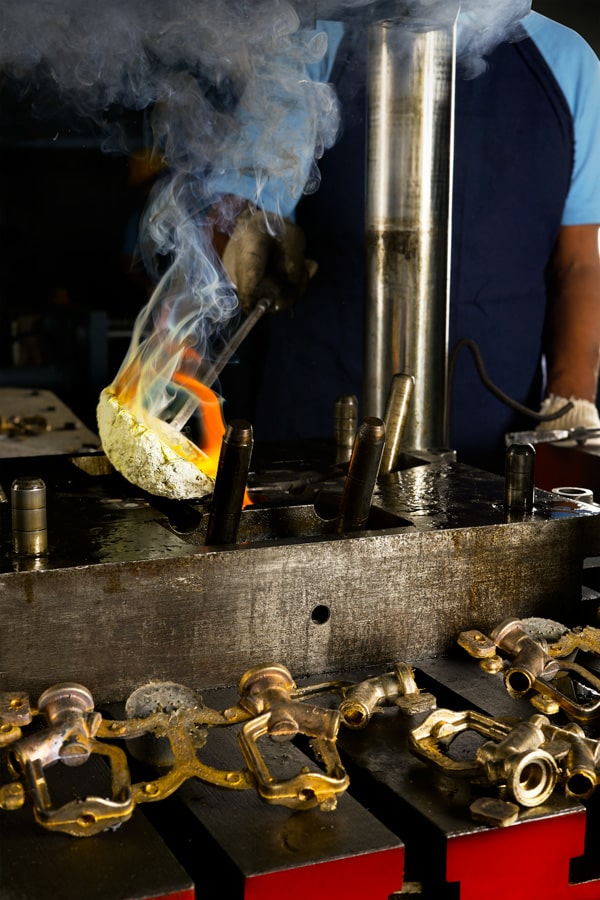 Worker pouring molten metal in foundry, process of metal casting.