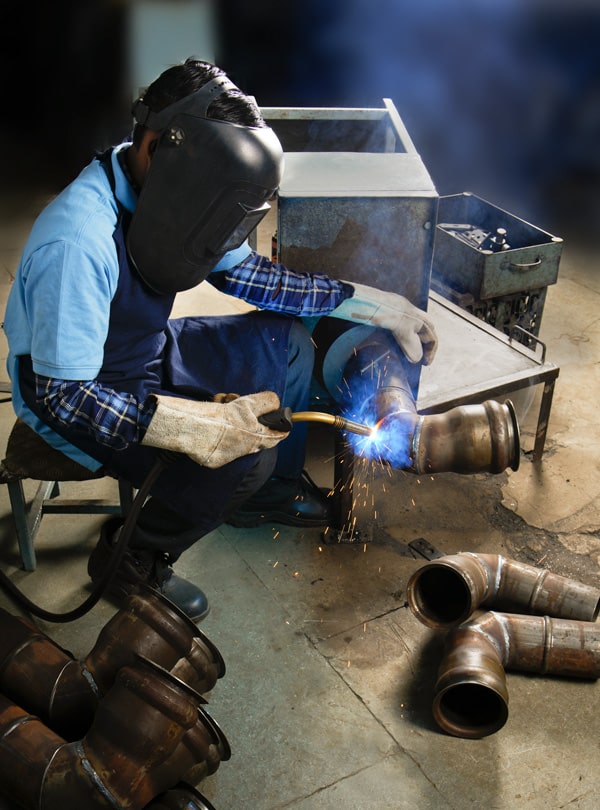 Welder with protective gear welding metal parts.