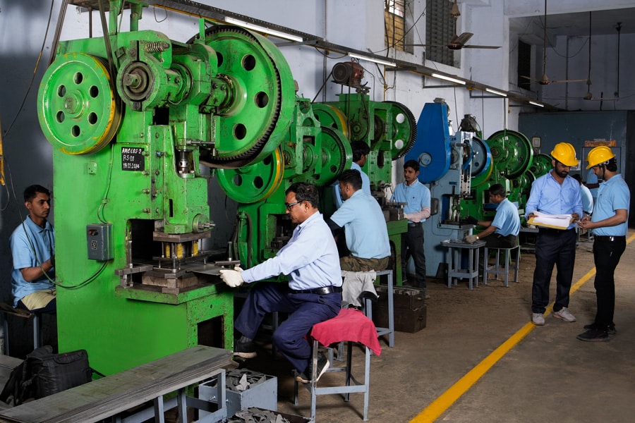 Industrial punching machine in operation with workers and supervisors.